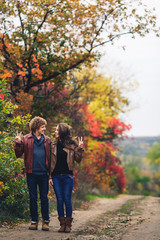 merry couple shows emotions. man and woman in leather jackets and jeans against background of autumn trees.