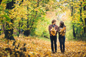 Fototapeta premium Loving happy couple in autumn in park holding autumn maple leaves in hands.