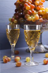 glass of young wine with grapes blue background - vintage