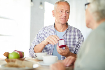 Fototapeta premium Aged man giving his wife new ring for family occasion or for her birthday while having tea