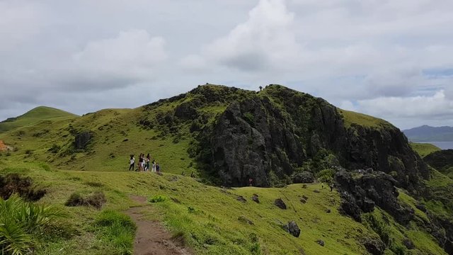 Tourists walking on a mountain in Batanes, Philippines.