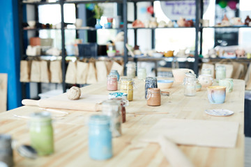 Group of supplies and handtools for pottery craft on wooden table in workshop