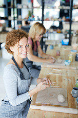 Happy young woman in apron sitting by table