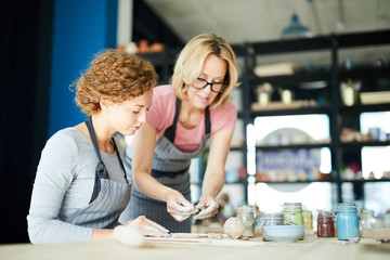 Pottery craft master showing her disciple how to make workpieces for earthenware
