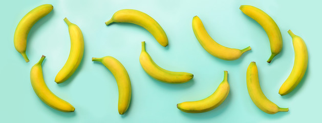 Chaotic colorful fruit pattern. Bananas over blue background. Banner. Top view. Pop art design, creative summer concept. Minimal flat lay style.