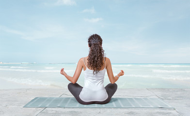 Young woman is meditating on the beach