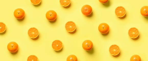 Fruit pattern of fresh orange slices on yellow background. Top view. Copy Space. Pop art design, creative summer concept. Half of citrus in minimal flat lay style. Banner.