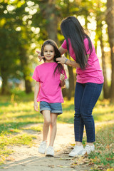 Young latin mother and daughter laughing in city park