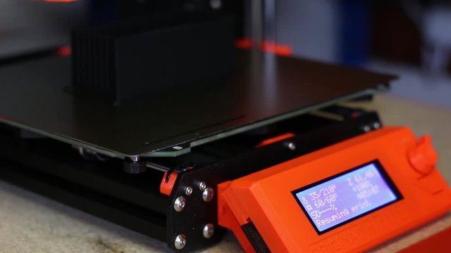 Close up of an LCD Screen on a 3D Printer - a hand interacts with a toggle and a button, resuming the print.