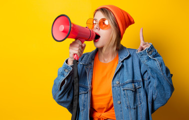 Young style girl in jeans clothes with pink megaphone on yellow background. Symbolizes female resistance. Clothes in 1980s style