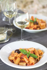 Italian dinner with Italian pasta with tomatoes and basil and white wine in authentic interior
