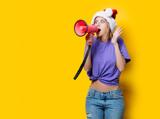Young style girl in purple clothes and Christmas hat with pink megaphone on yellow background. Symbolizes female resistance. Clothes in 1980s style