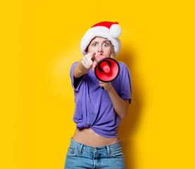 Young style girl in purple clothes and Christmas hat with pink megaphone on yellow background. Symbolizes female resistance. Clothes in 1980s style