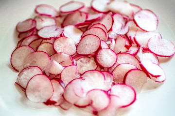 Plate full of freshly cut radishes on the kitchen counter waiting for the chef to use in a recipe.