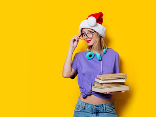 Young style girl in purple clothes and Christmas hat and books on yellow background.  Clothes in 1980s style