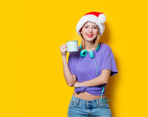 Young style girl in purple clothes and Christmas hat and cup on yellow background.  Clothes in 1980s style