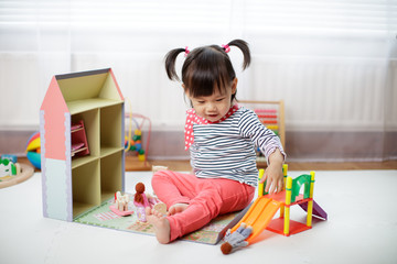 baby girl playing doll house at home