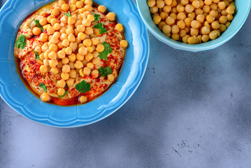 Chickpea hummus topped with olive oil, pepper, parsley, spices on a shabby modern table silver tray or Abstract cement concrete background grey.Hummus Traditional Middle Eastern food.Copy space.