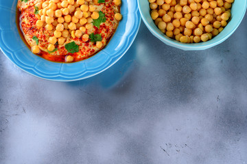 Chickpea hummus topped with olive oil, pepper, parsley, spices on a shabby modern table silver tray or Abstract cement concrete background grey.Hummus Traditional Middle Eastern food.Copy space.