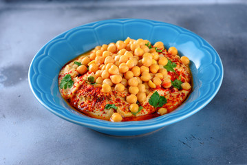 Chickpea hummus and tahini topped with olive oil, pepper, parsley, spices on Abstract background grey. Hummus Traditional Middle Eastern food commonly served in a pita.