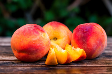 Fototapeta na wymiar Fresh ripe peaches and slices on wooden table