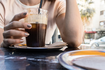 Fototapeta na wymiar a girl drinking cold coffee while talking at hot summer day
