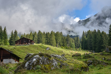 Fototapeta na wymiar Idyllic view of wooden mountain farm houses in the Swiss Alps, shrouded in mist