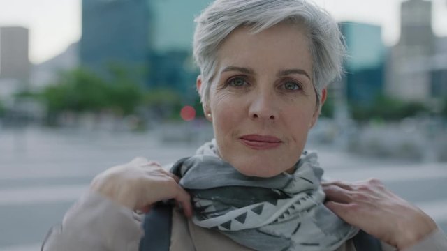 portrait of confident mature caucasian woman looking serious wearing scarf in urban city background