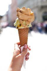 melting delicious ice cream in waffle cone gelato pistachio salty caramel holding female hand - obrazy, fototapety, plakaty