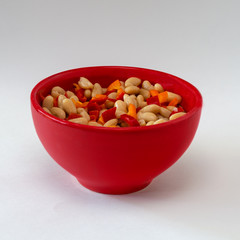 Navy beans and red and orange peppers in red bowl isolated on white