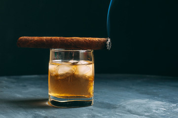 Whiskey on the rocks and a cigar. Top view with copy space.