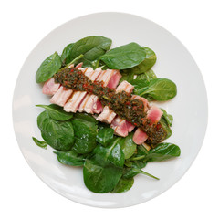 Grilled tuna with spinach and chimichurri sauce isolated on white