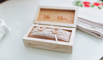 Two golden wedding rings in a wooden box on a soft pillow. Choosing wedding rings. Preparation for the ceremony.
