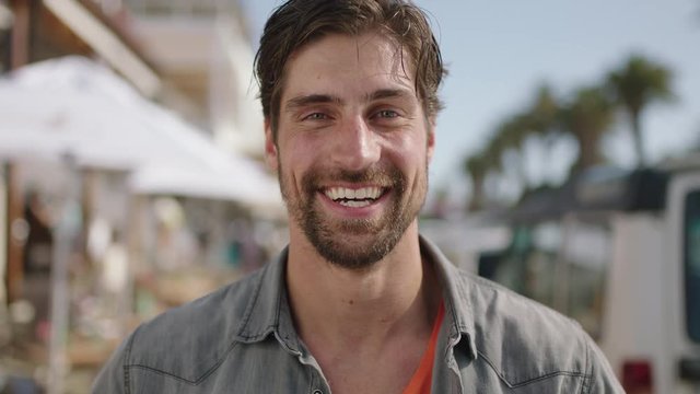 portrait of attractive man laughing enjoying sunny beachfront on vacation