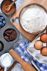 Food background. Ingredients for baking: flour, eggs, berries, chocolate on a concrete background.
