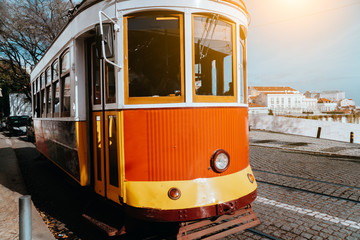 Fototapeta na wymiar Lisbon traditional red tram on a street in Alfama district near terasse. Portugal, Europe