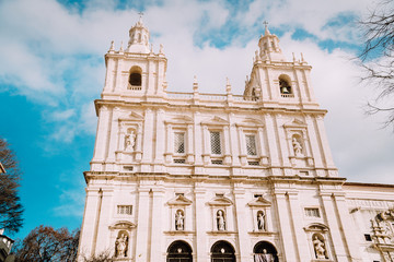 Obraz premium Facade of Monastery of Sao Vicente de Fora in Alfama, Lisbon against blue sky with white clouds. The monastery contains the royal pantheon of the Braganza monarchs of Portugal