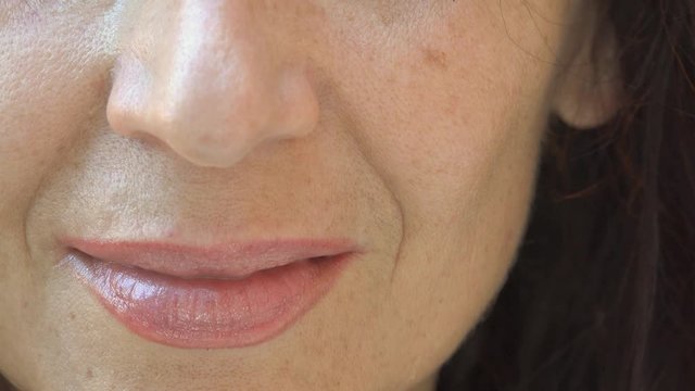 mature woman smiling and lapping shimmering lipstick on cracked lips with tongue, showing mature skin with aging spots, neo,  wrinkles and moustaches