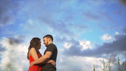 Young happy couple kissing in nature against the setting sun at sunset. Beautiful, girl, boyfriend, hugging, against, sky., Young, couple, sunset, background.