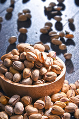 Composition with bowl of pistachio on wooden table. Delicacies