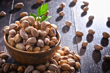 Composition with bowl of pistachio on wooden table. Delicacies