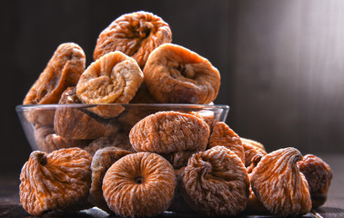 Composition with bowl of dried figs on wooden table