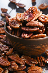Bowl with pecan nuts on wooden table.