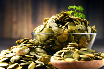 Composition with bowl of pumpkin seeds on wooden table