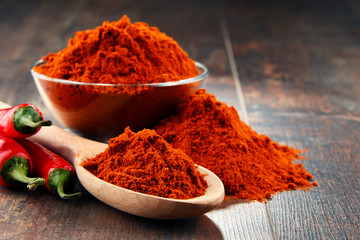 Composition with bowl of chili powder on wooden table