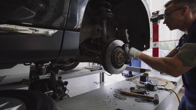 Car mechanic Repairing brakes on car in modern service workshop