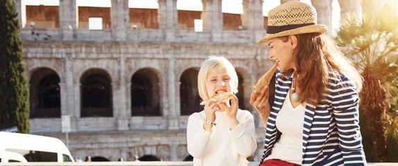 mother and child tourists in front of Colosseum eating pizza