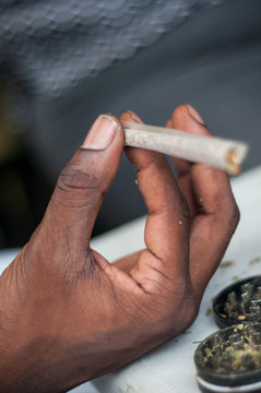 closeup of african man rolling a joint of cannabis in outdoor