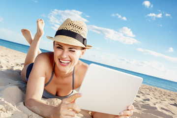 smiling modern woman in beachwear with tablet PC on seashore