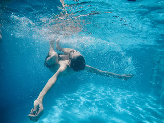 young man under the water of a swimming pool